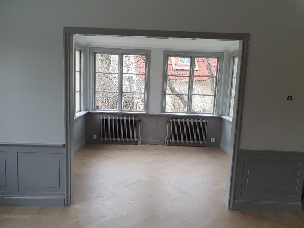 Burspråk med gråmålade bröstpaneler, fönster och foder