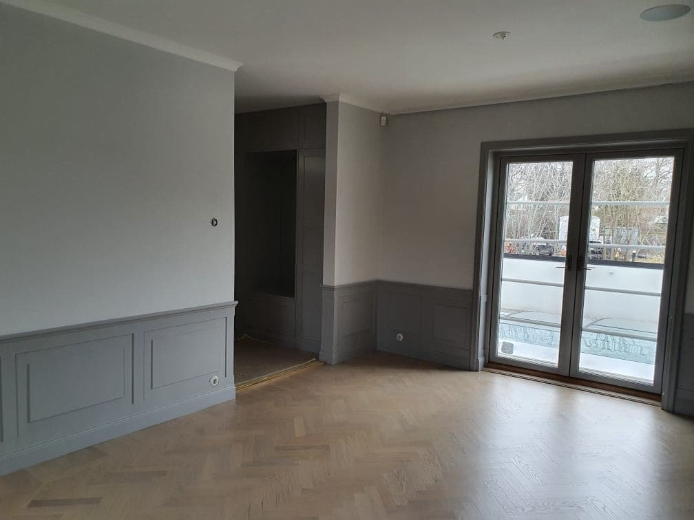 Rum med grå bröstpanel, inbyggd garderob och målad balkongdörr