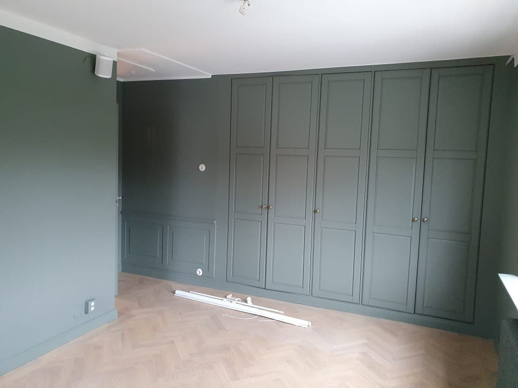 Sovrum med gröna väggar, panel och garderobsdörrar i samma kulör