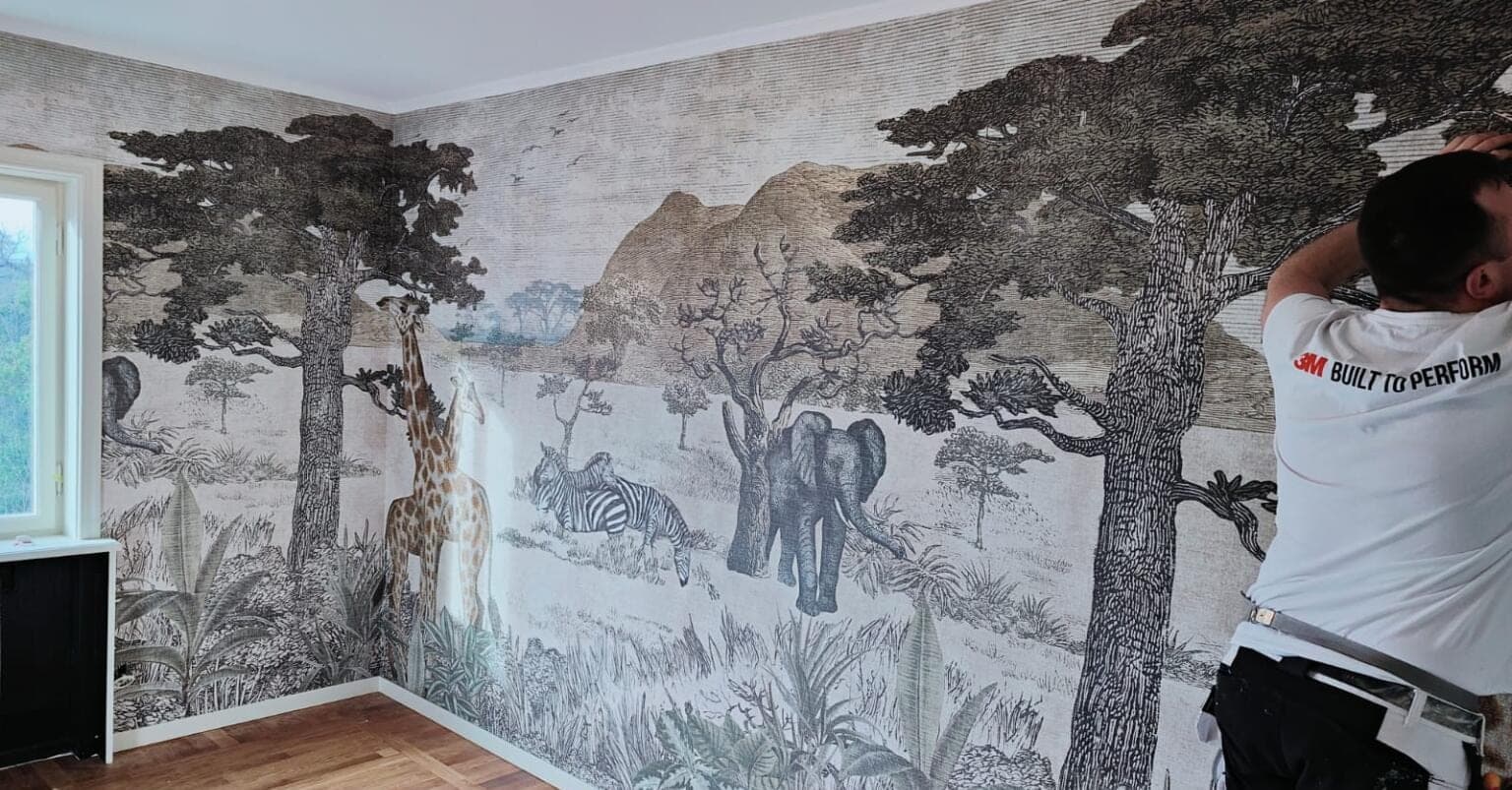 Målare sätter upp fototapet med savannmotiv